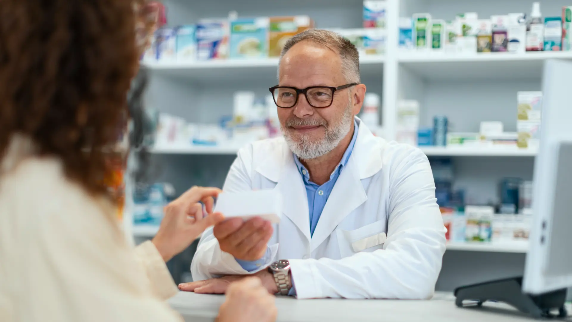 Farmacêutico entregando um medicamento no balcão de uma farmácia